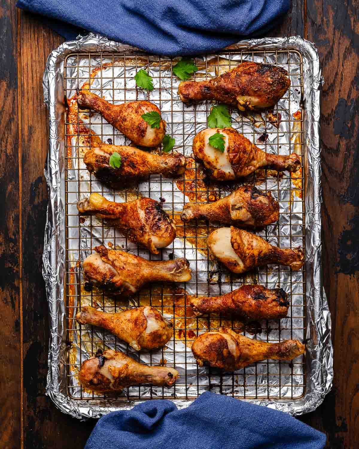 Baked Cajun chicken legs on wire rack with foil.