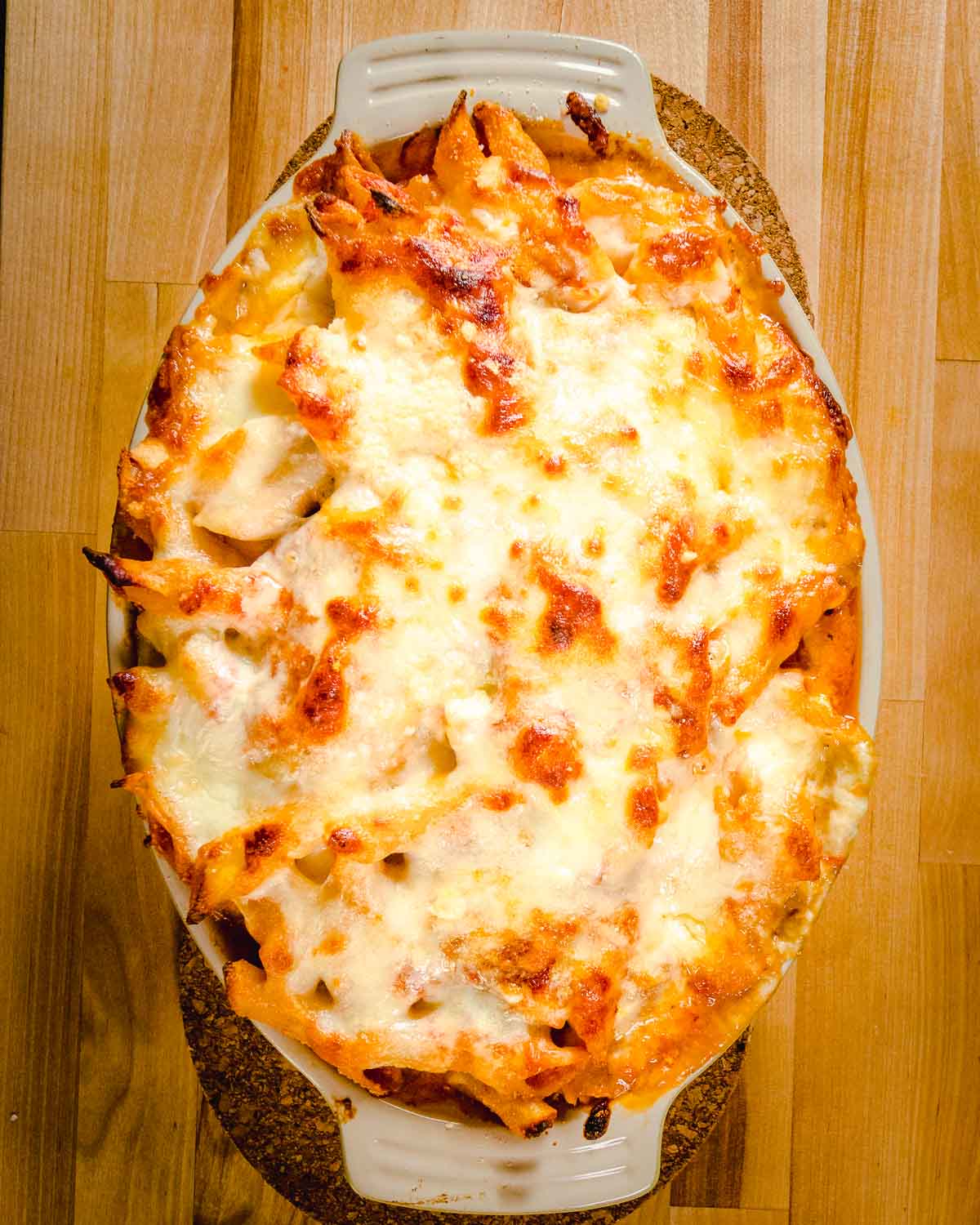 Overhead view of finished baked ziti in oval bowl.