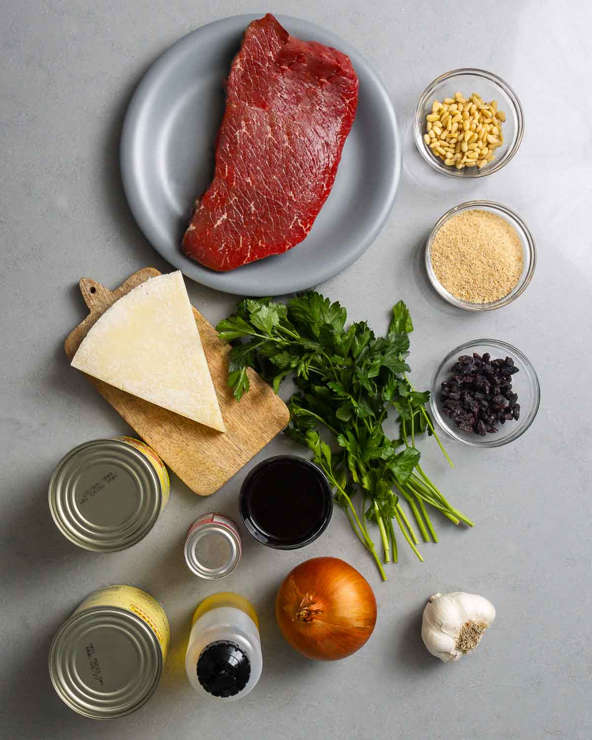 Ingredients shown: top round, pine nuts, breadcrumbs, raisins, Pecorino Romano, parsley, canned tomatoes, onion, red wine, olive oil, and garlic.