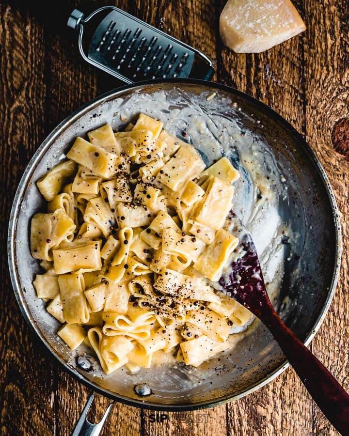 Calamarata cacio e pepe in large pan.