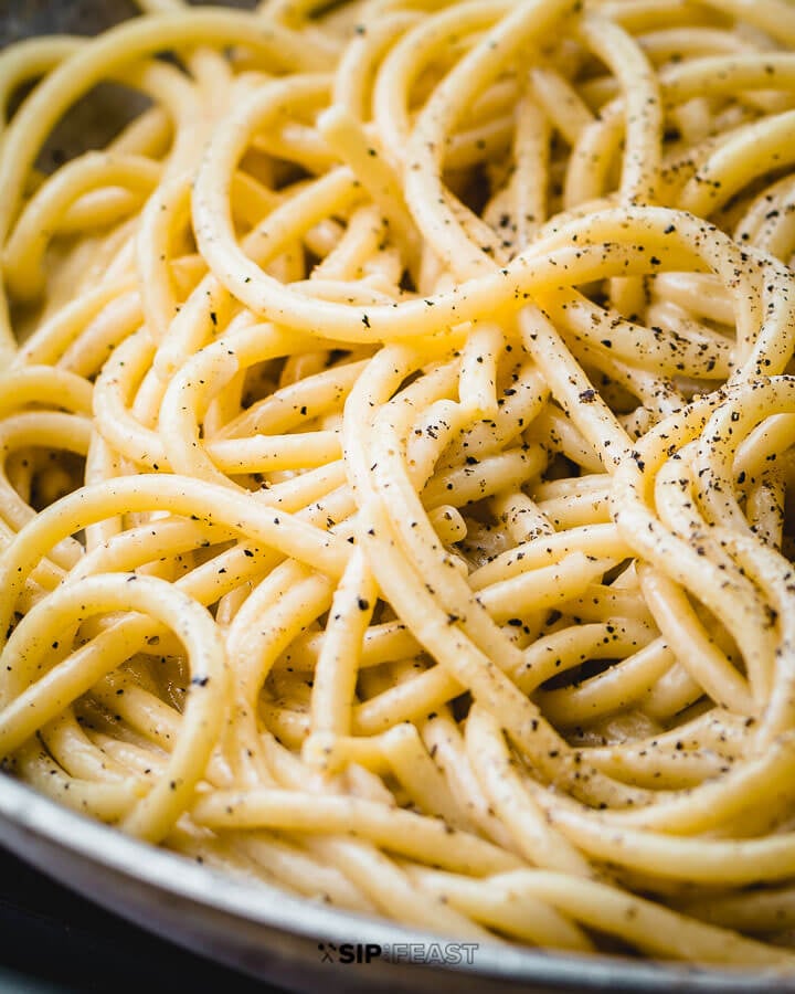 Cacio e pepe in pan with sprinkled pepper.