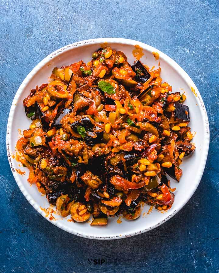 Bowl of caponata on blue table.