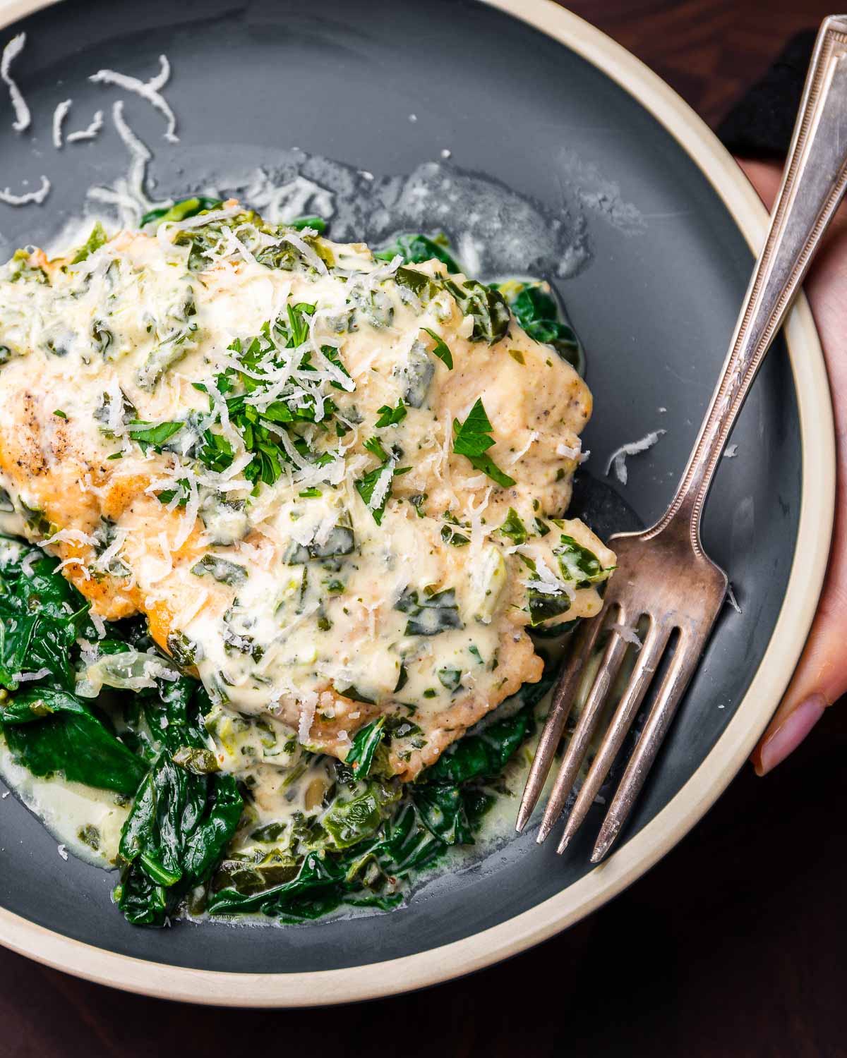 Hands holding chicken Florentine in blue dish.