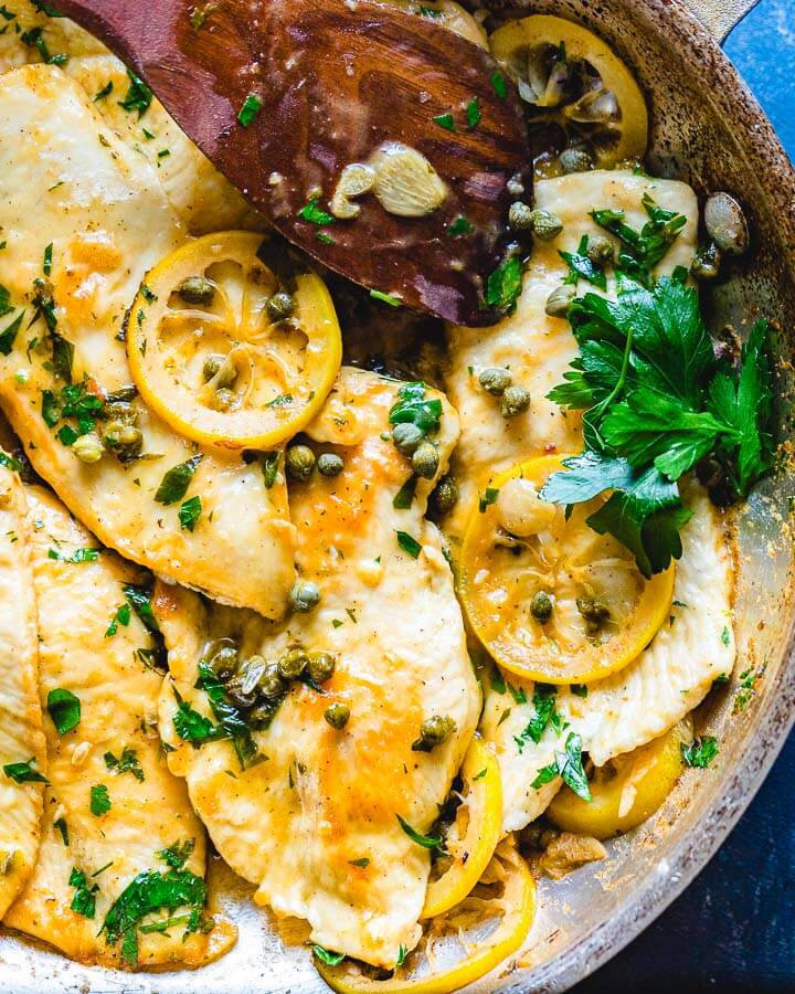 Chicken Piccata in pan with big piece of parsley.