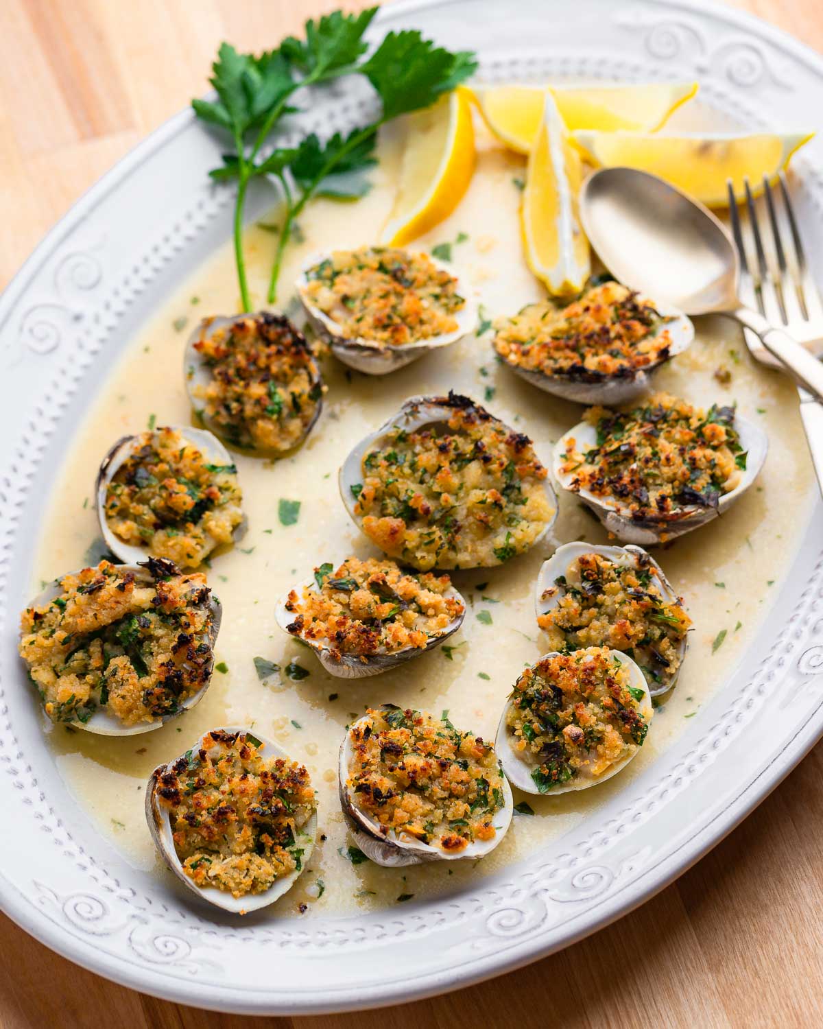 Full plate of cooked clams oreganata on wood table.