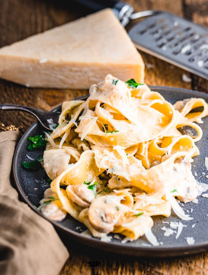 Plated pasta recipe with Pecorino Romano cheese block and grater.