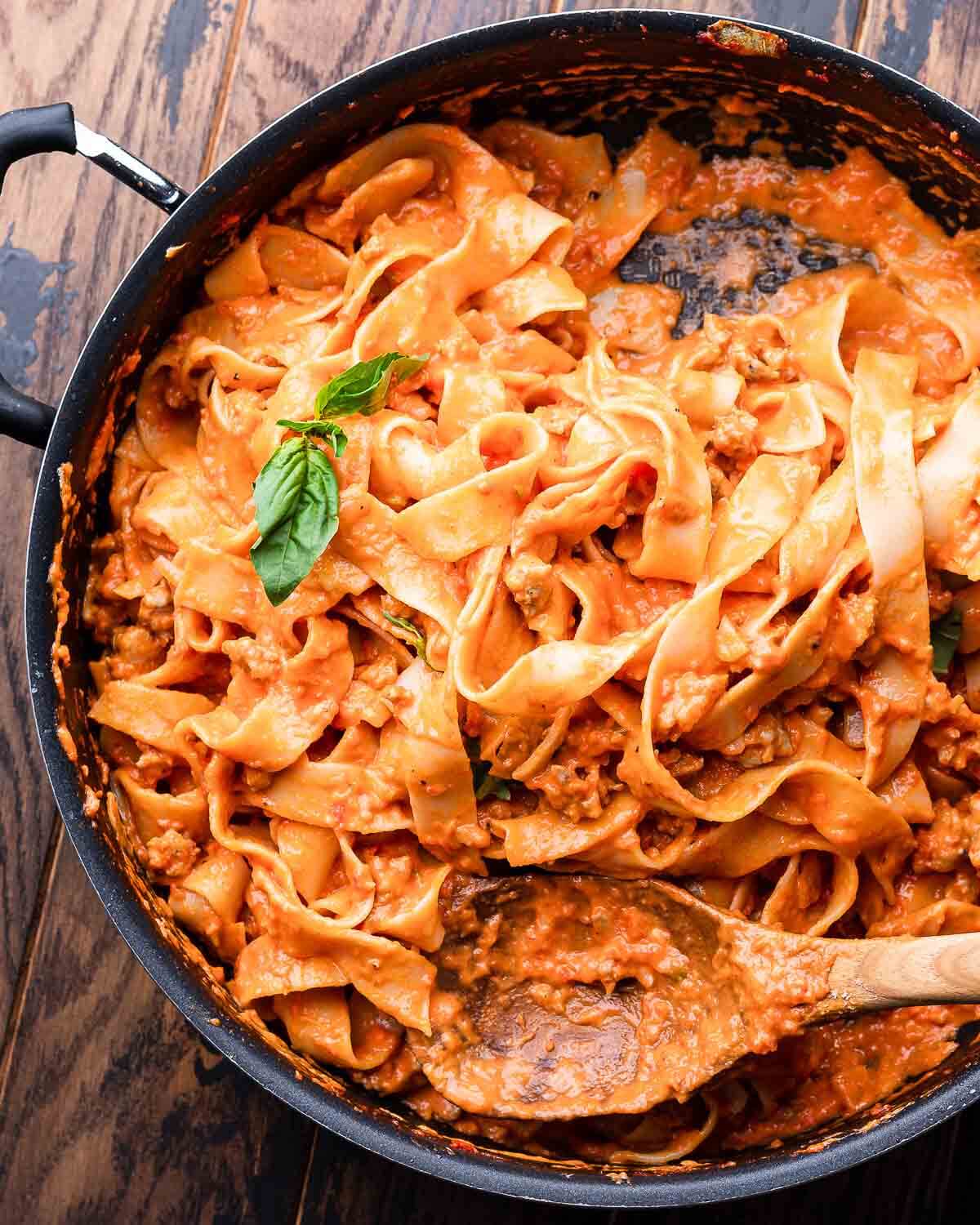 Overhead shot of black pan with creamy Italian sausage pasta.