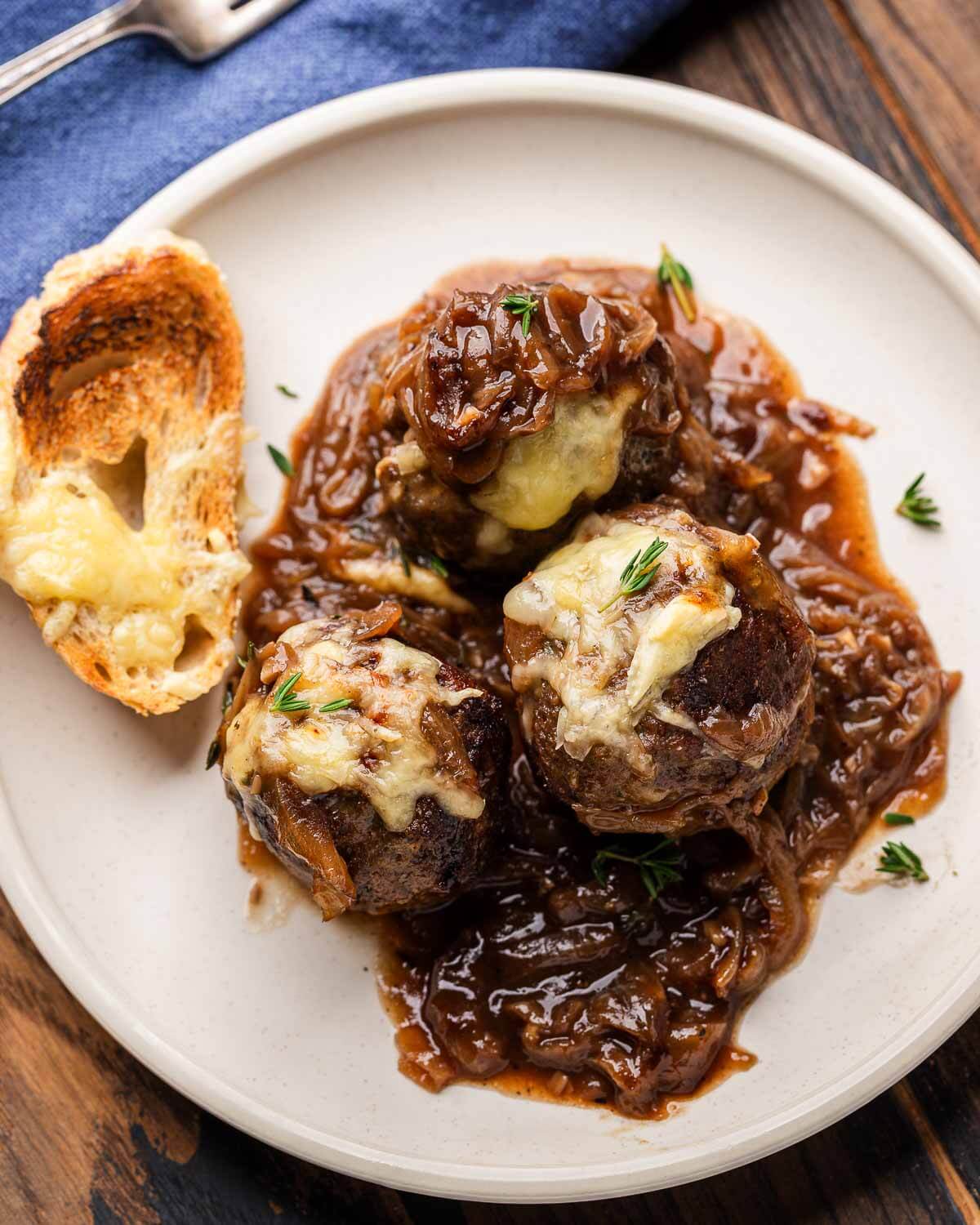 White plate with 3 meatballs and toasted baguette.