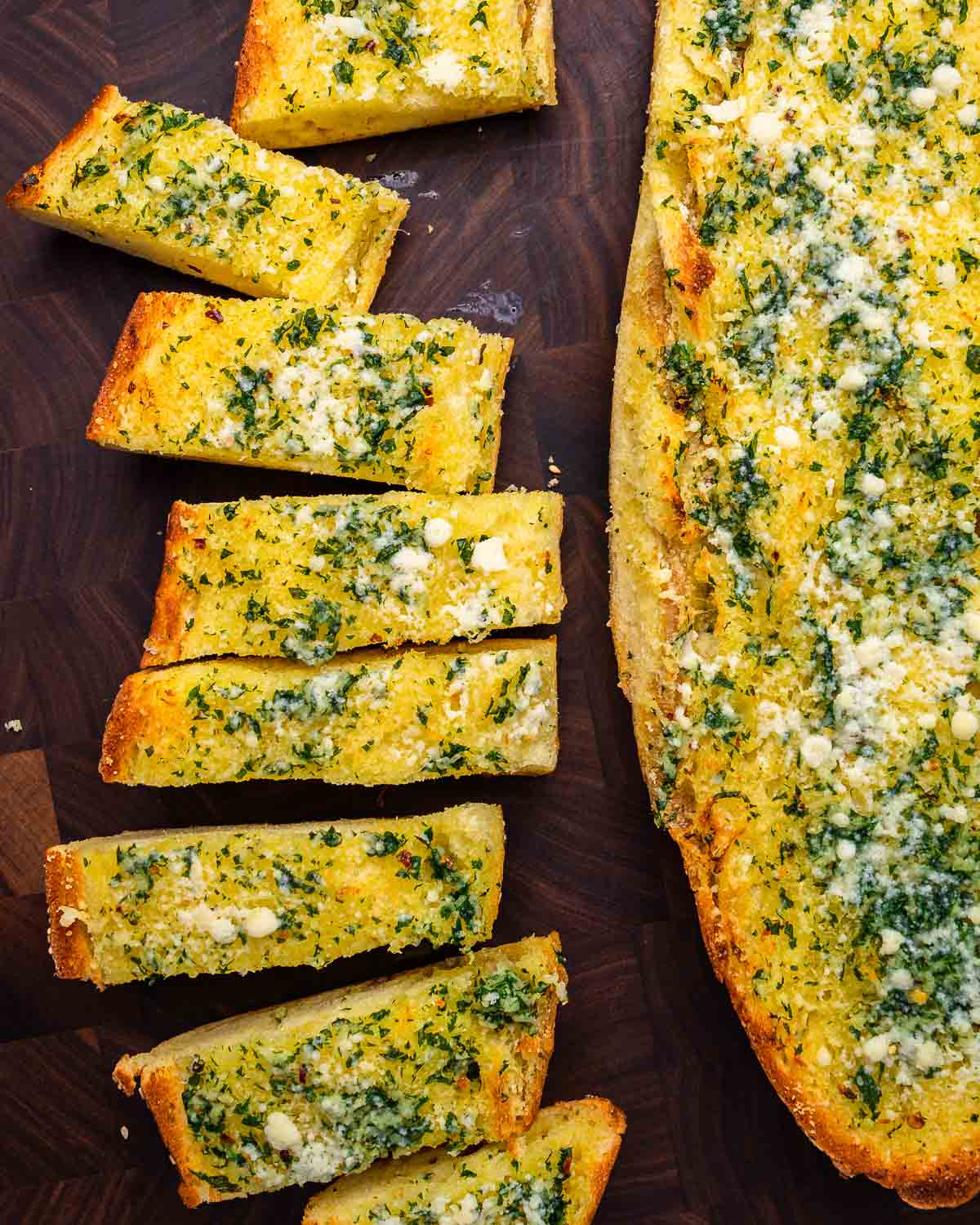 Overheat shot of garlic bread cut into pieces on cutting board.