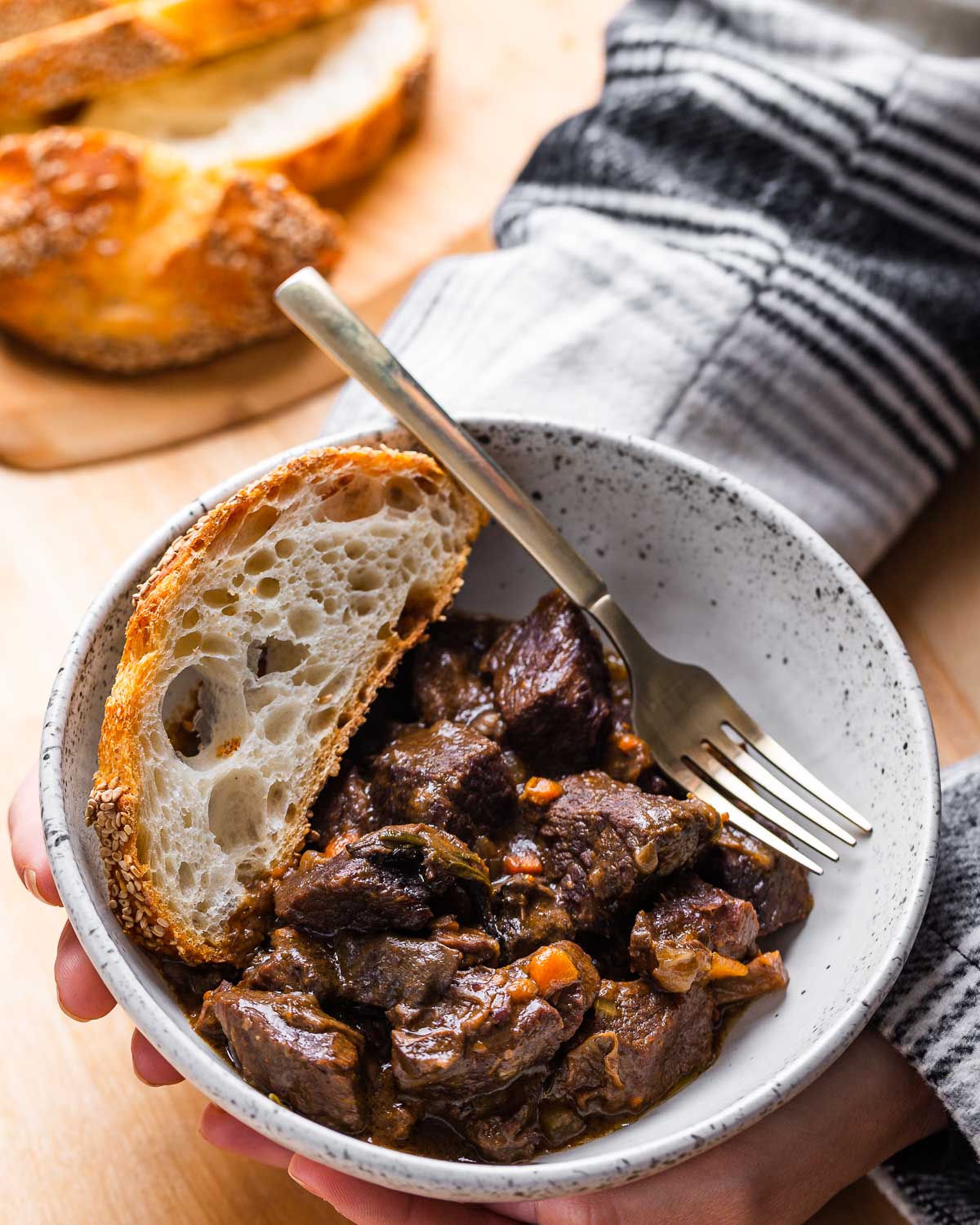 Italian beef stew (spezzatino di manzo) in white bowl held in hands.