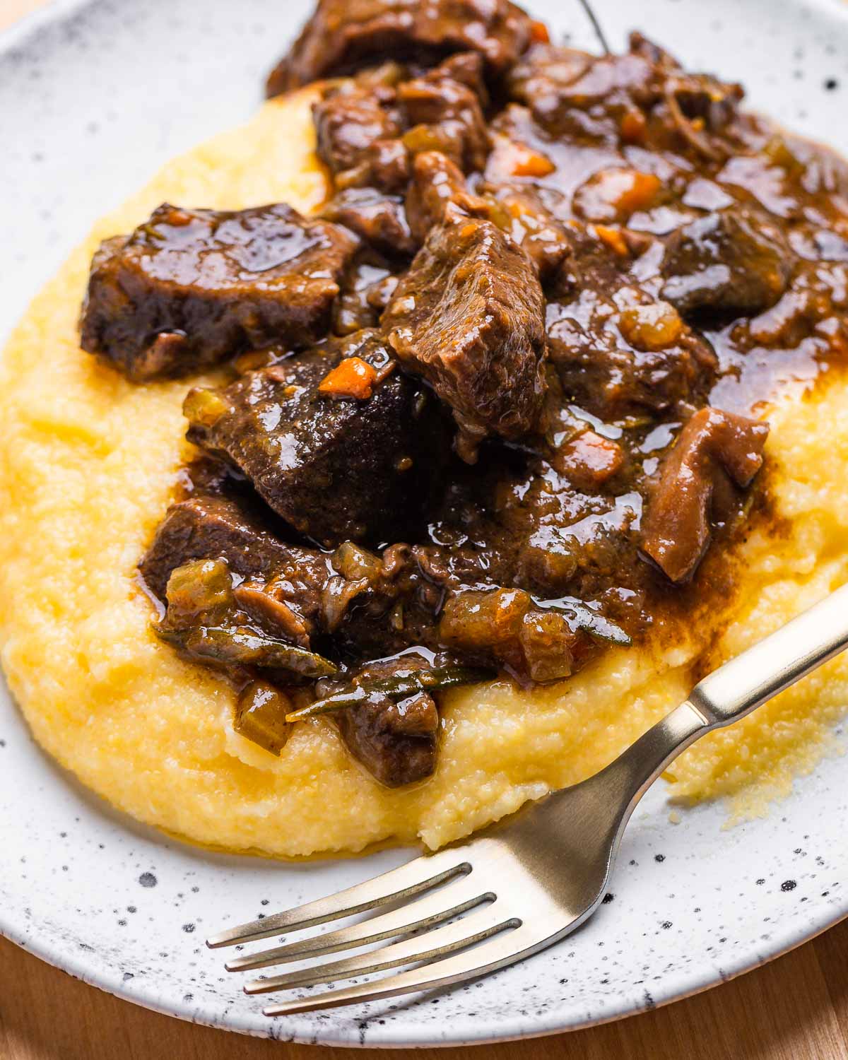 Italian beef stew over polenta in white dish.