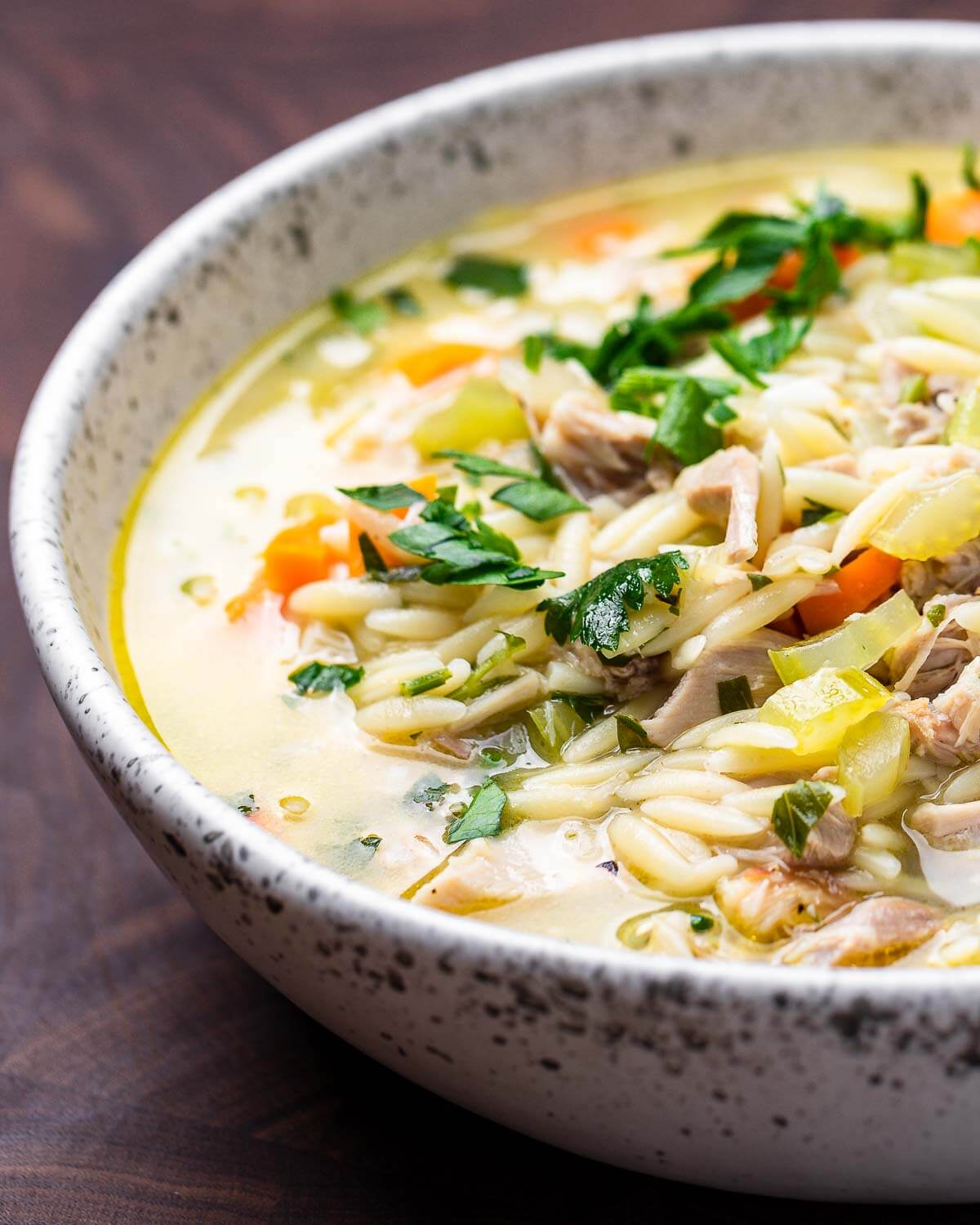 Lemon chicken orzo soup in white bowl.