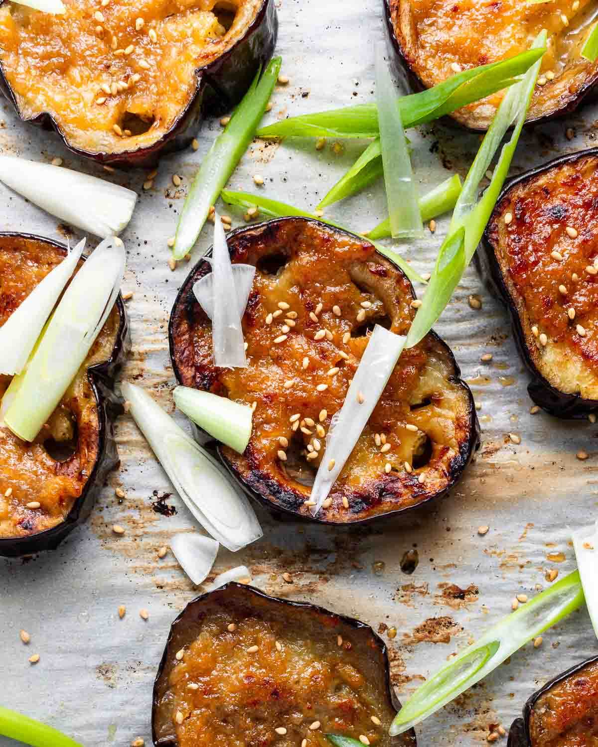 Nobu-style miso eggplant with white miso and green onions on baking sheet.