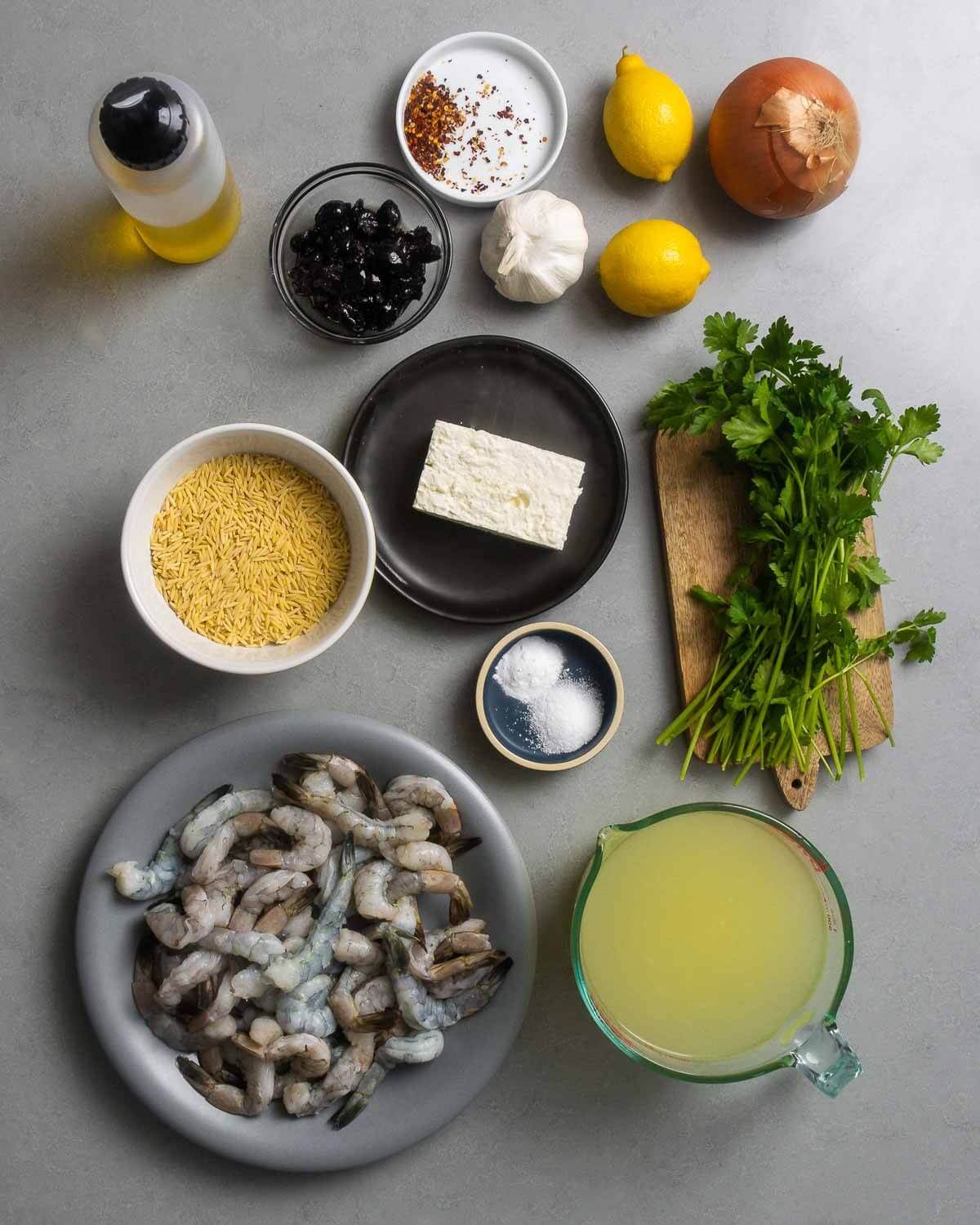 Ingredients shown: olive oil, oil-cured olives, red pepper flakes, garlic, lemons, onion, orzo, feta, salt, baking soda, parsley, shrimp, and chicken stock.