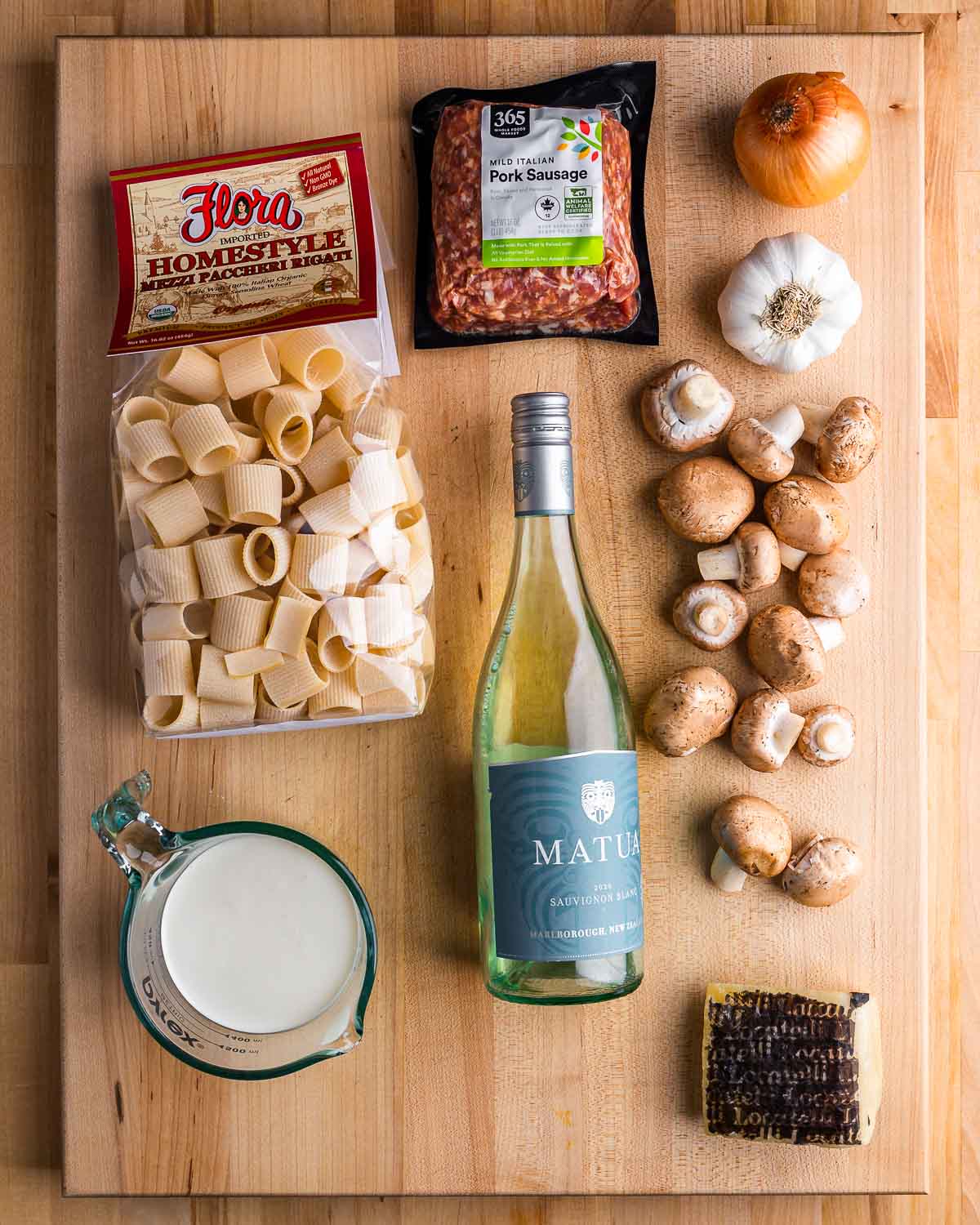 Ingredients shown: paccheri pasta, sausage, onion, garlic, mushrooms, cream, white wine, and Pecorino Romano.