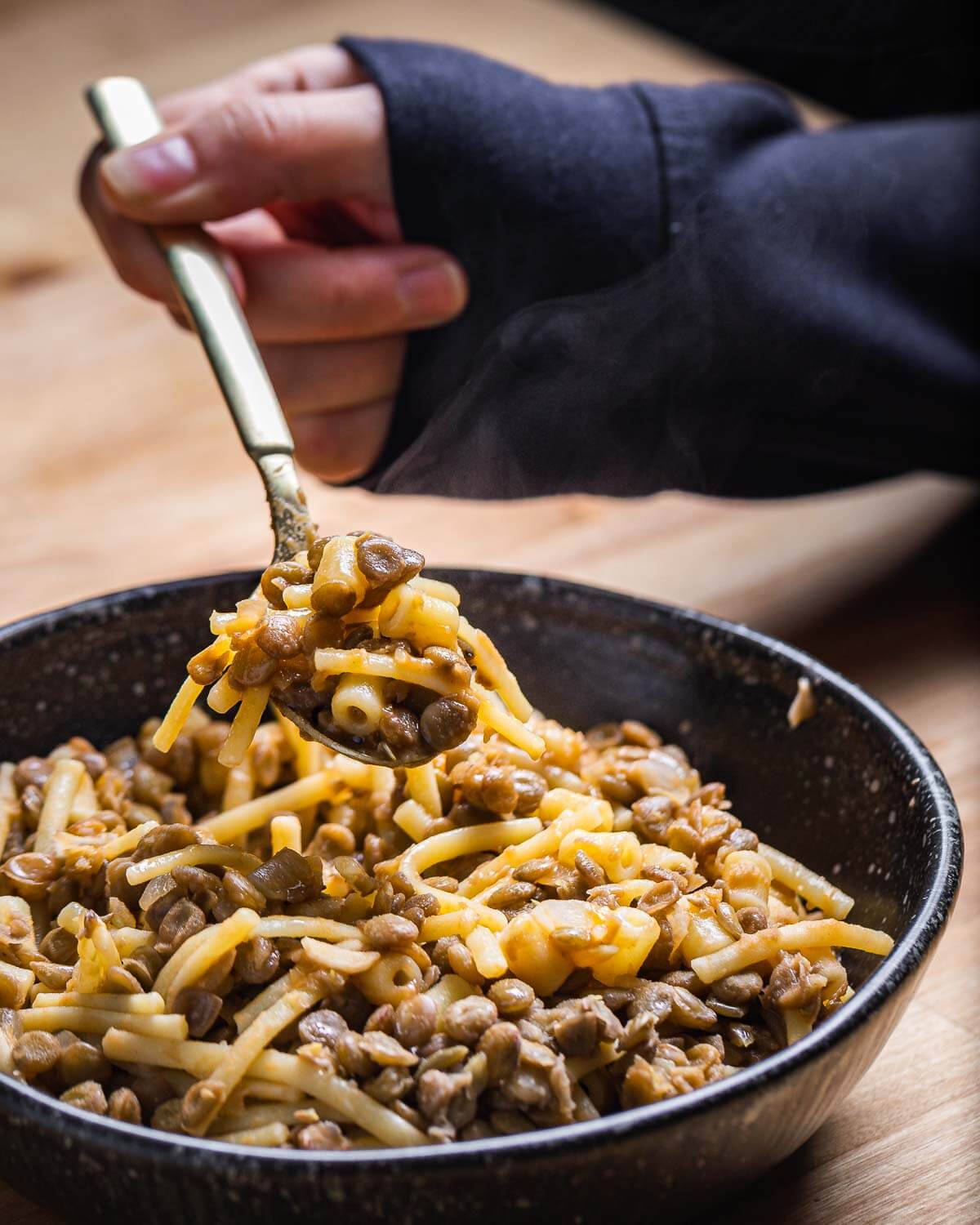 Hand holding spoonful of pasta e lenticchie.