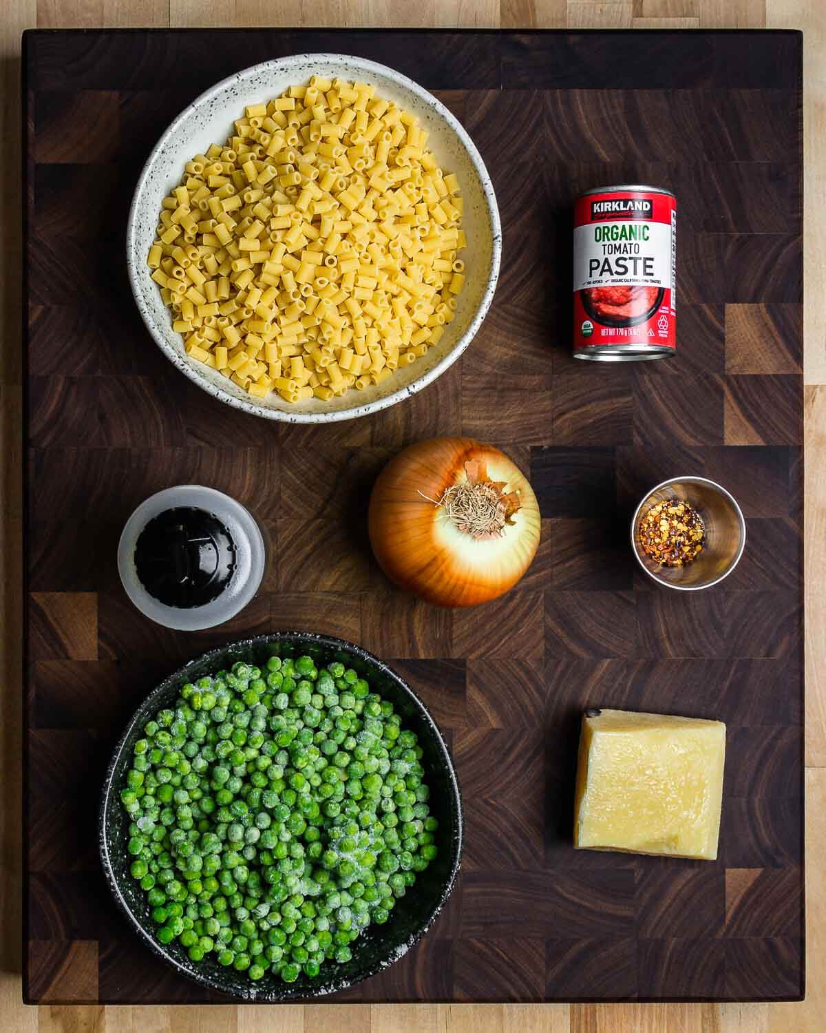 Ingredients shown: pasta, tomato paste, olive oil, onion, hot red pepper flakes, peas, and Pecorino Romano.