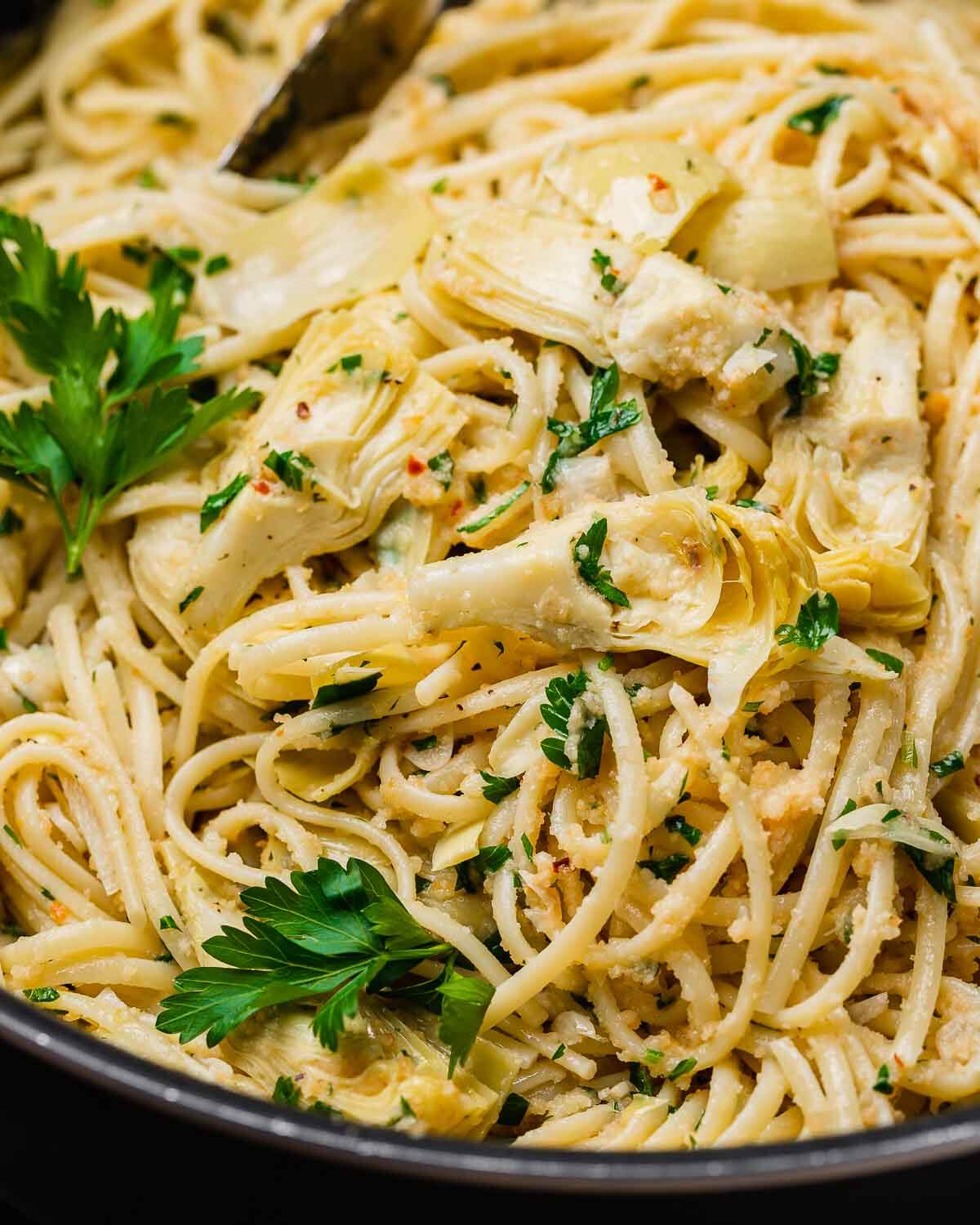 Closeup shot of pan with pasta and artichoke hearts.