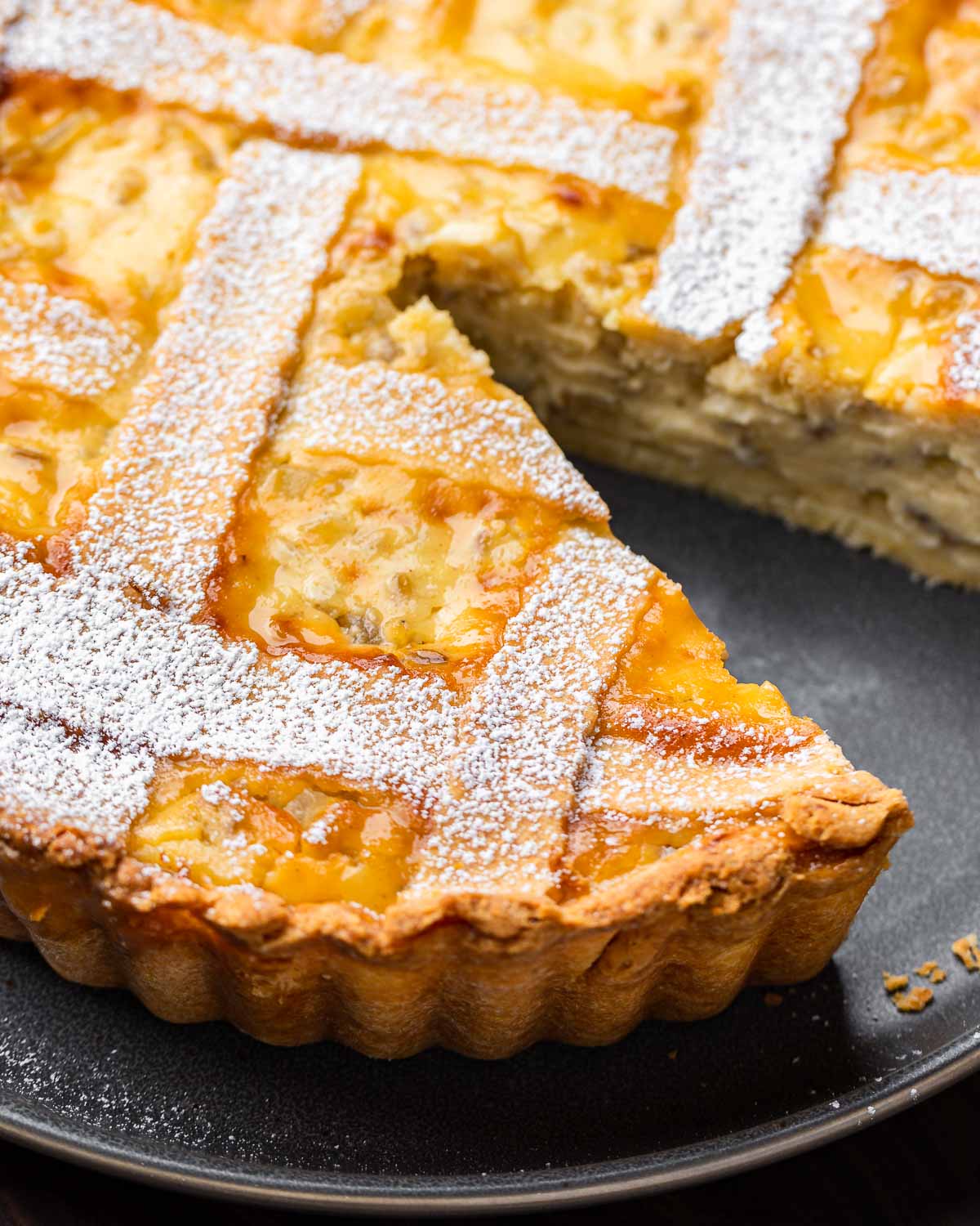 Pastiera Napoletana pie with slice removed in grey plate.