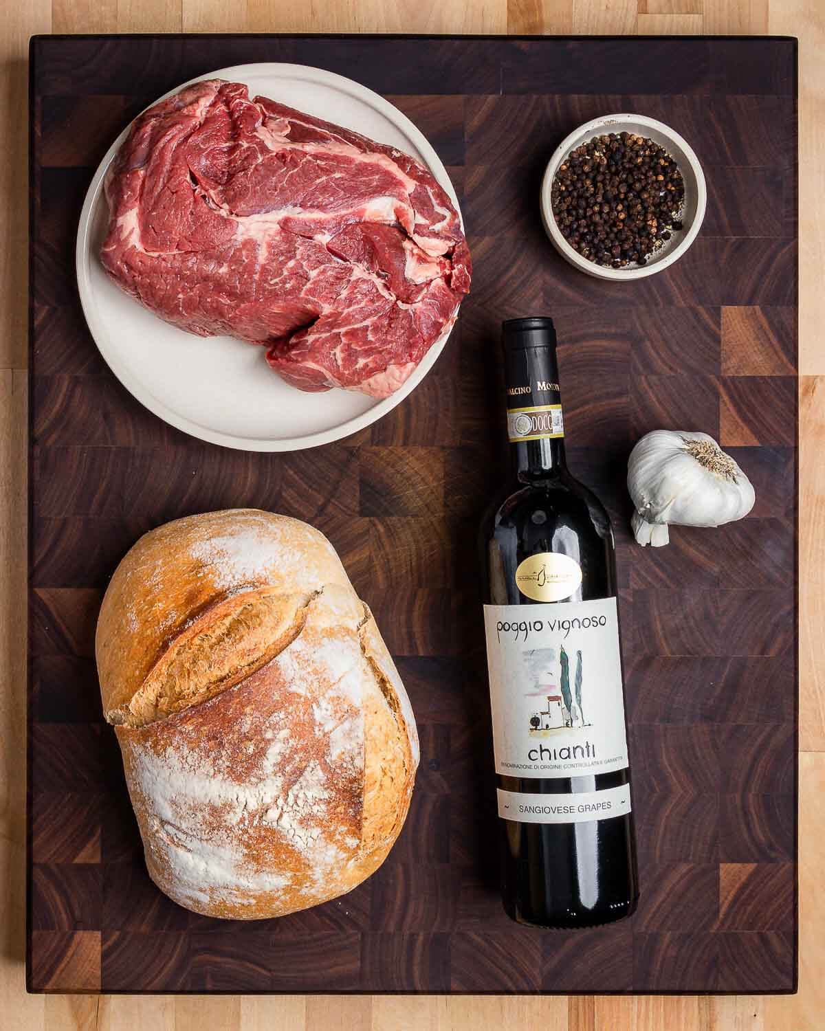 Ingredients shown: beef chuck, black peppercorns, rustic bread, bottle of chianti, and garlic.