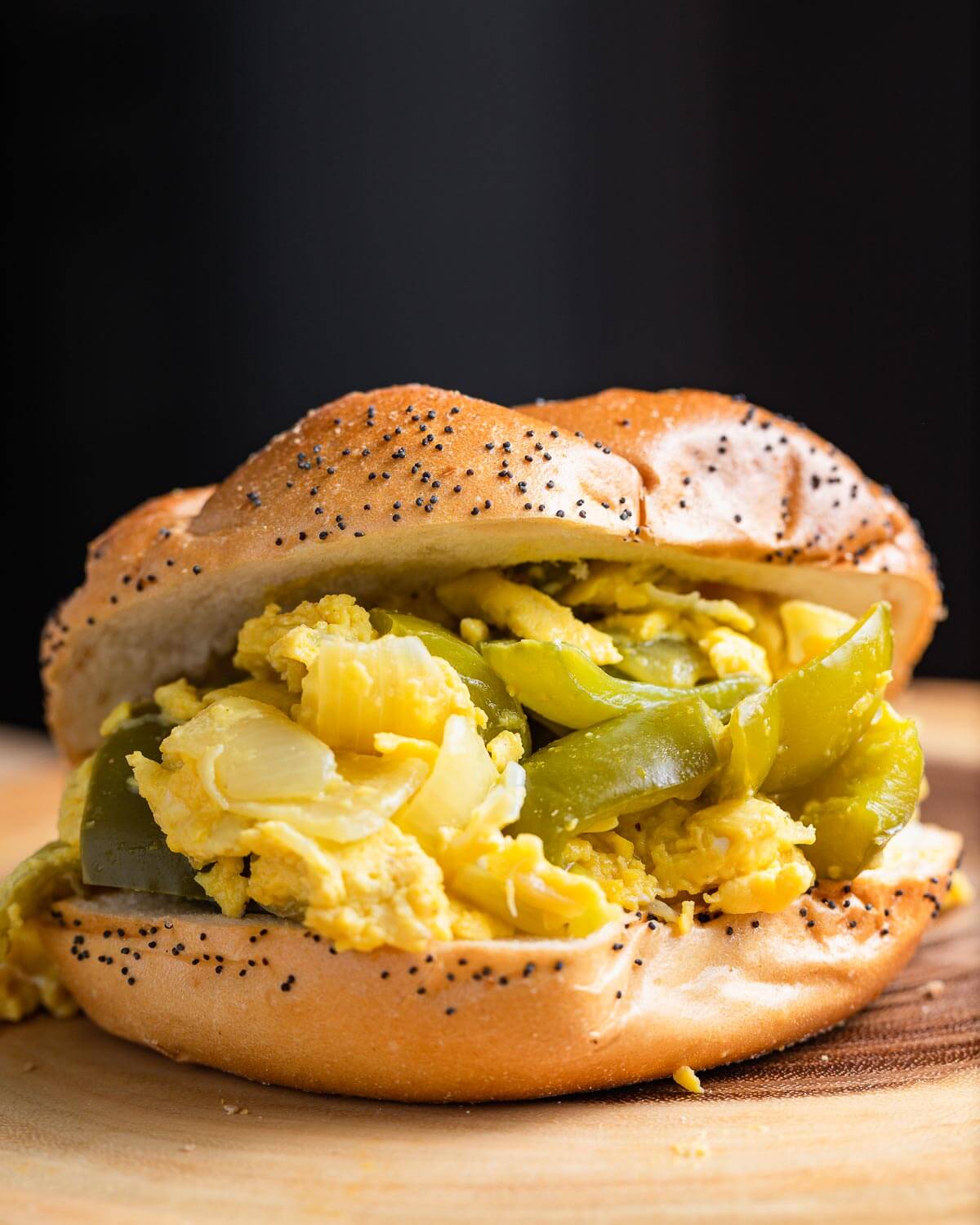 Pepper and egg sandwich on wood board.