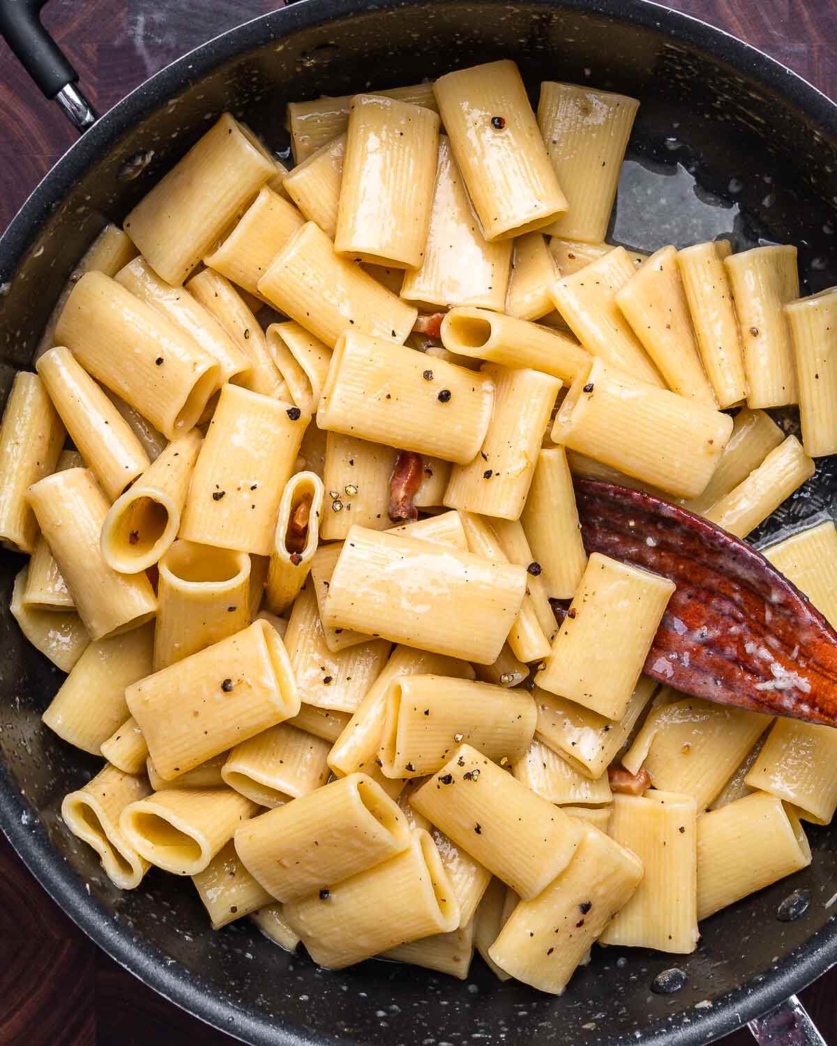 Overhead shot of rigatoni alla gricia in black pan.