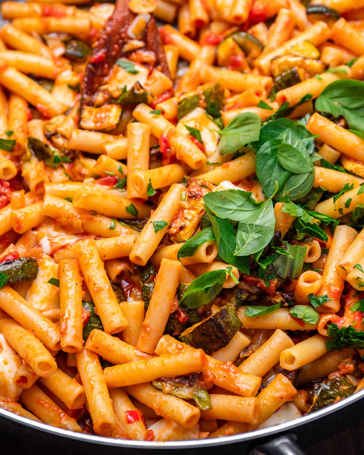 Large pan of roasted zucchini pasta with a lot of basil on top.