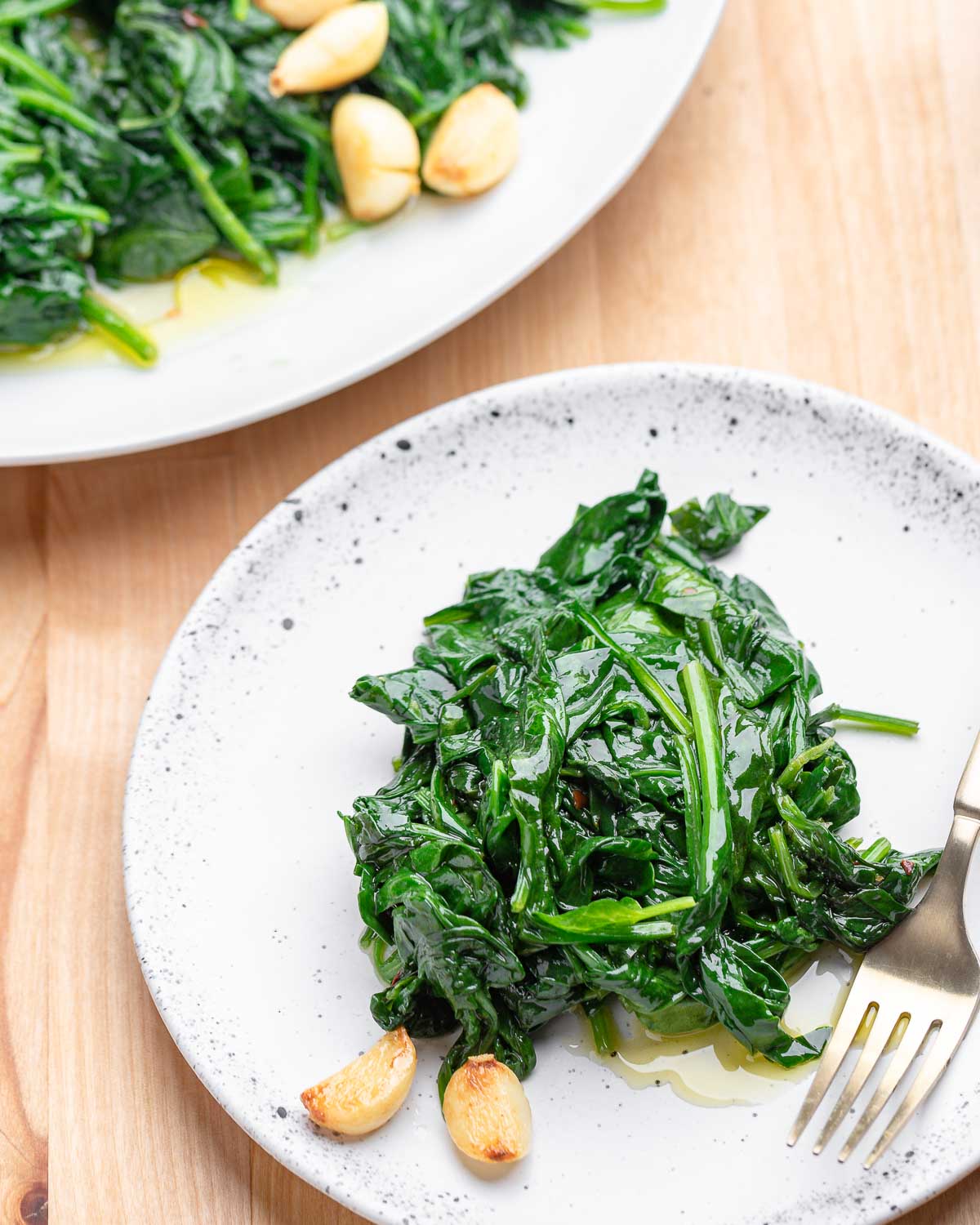 Small white plate with sauteed spinach.