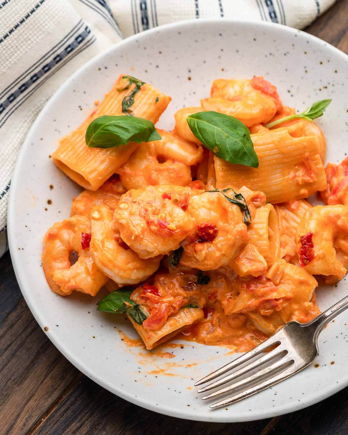 White plate with shrimp alla vodka along with napkin.