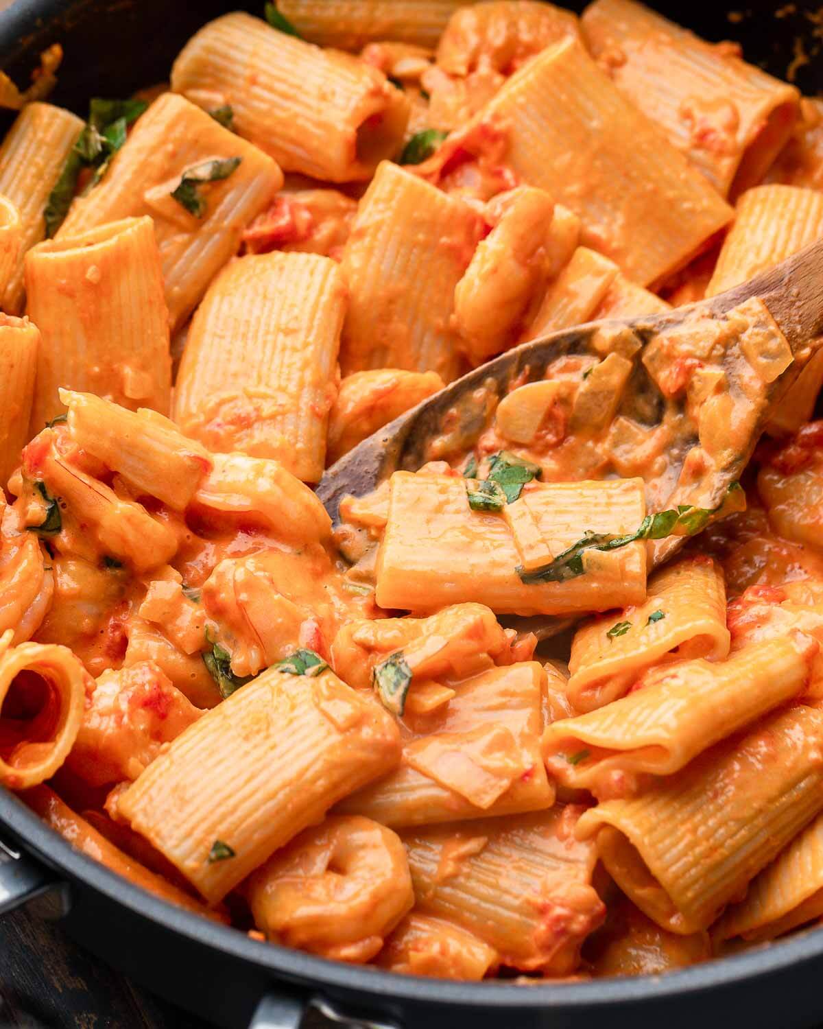 Closeup shot of vodka sauce shrimp pasta in black pan.