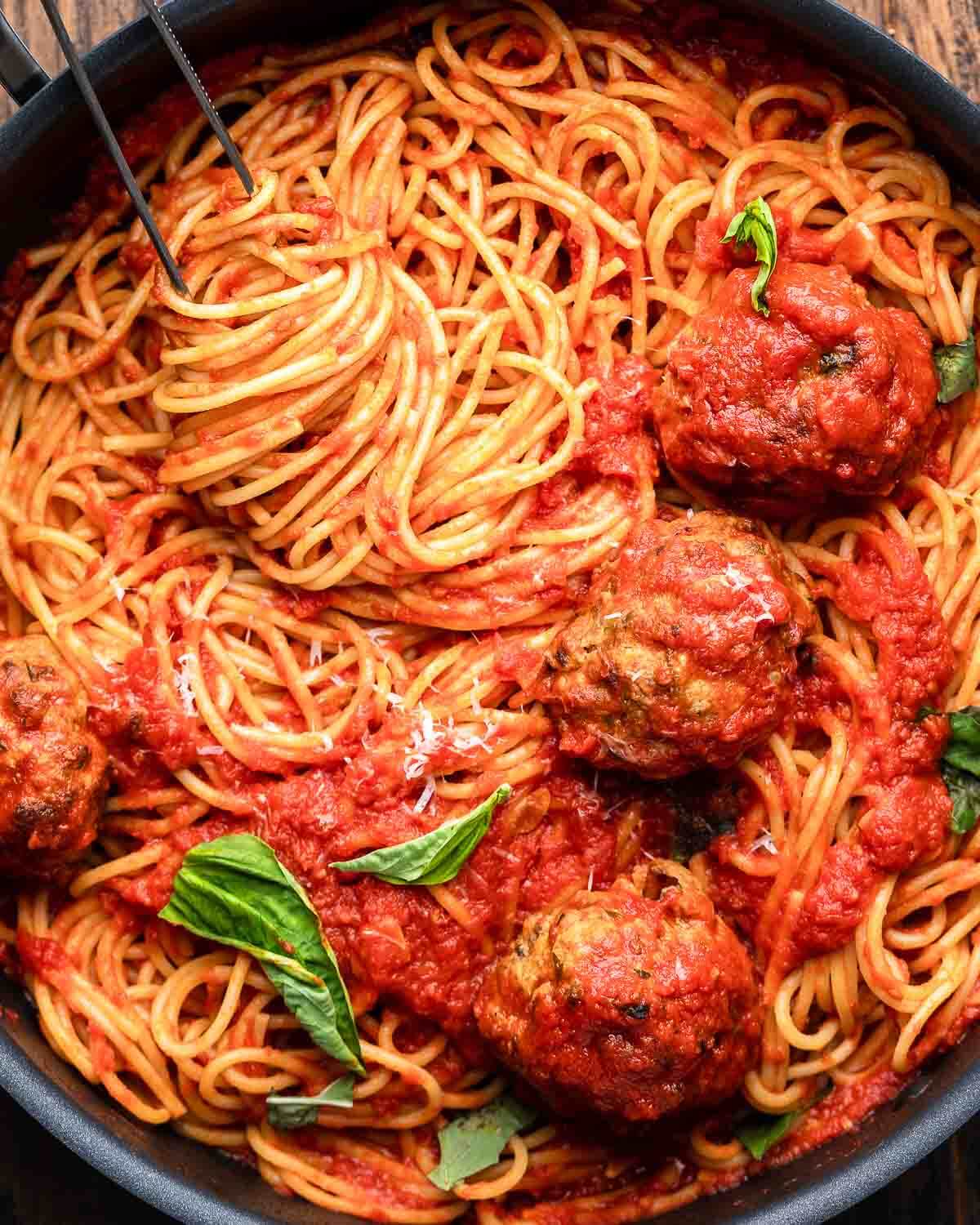 Overhead shot of spaghetti and meatballs in black pan.