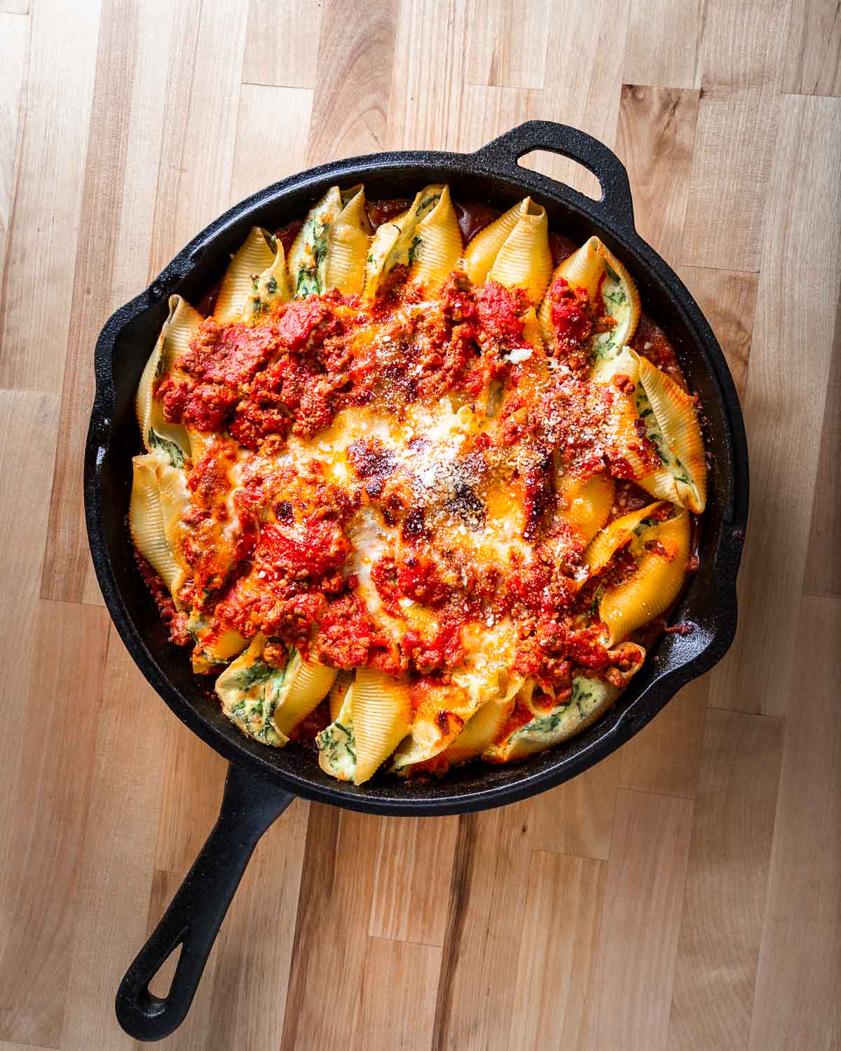 Overhead shot of full pan of stuffed shells on wood table.