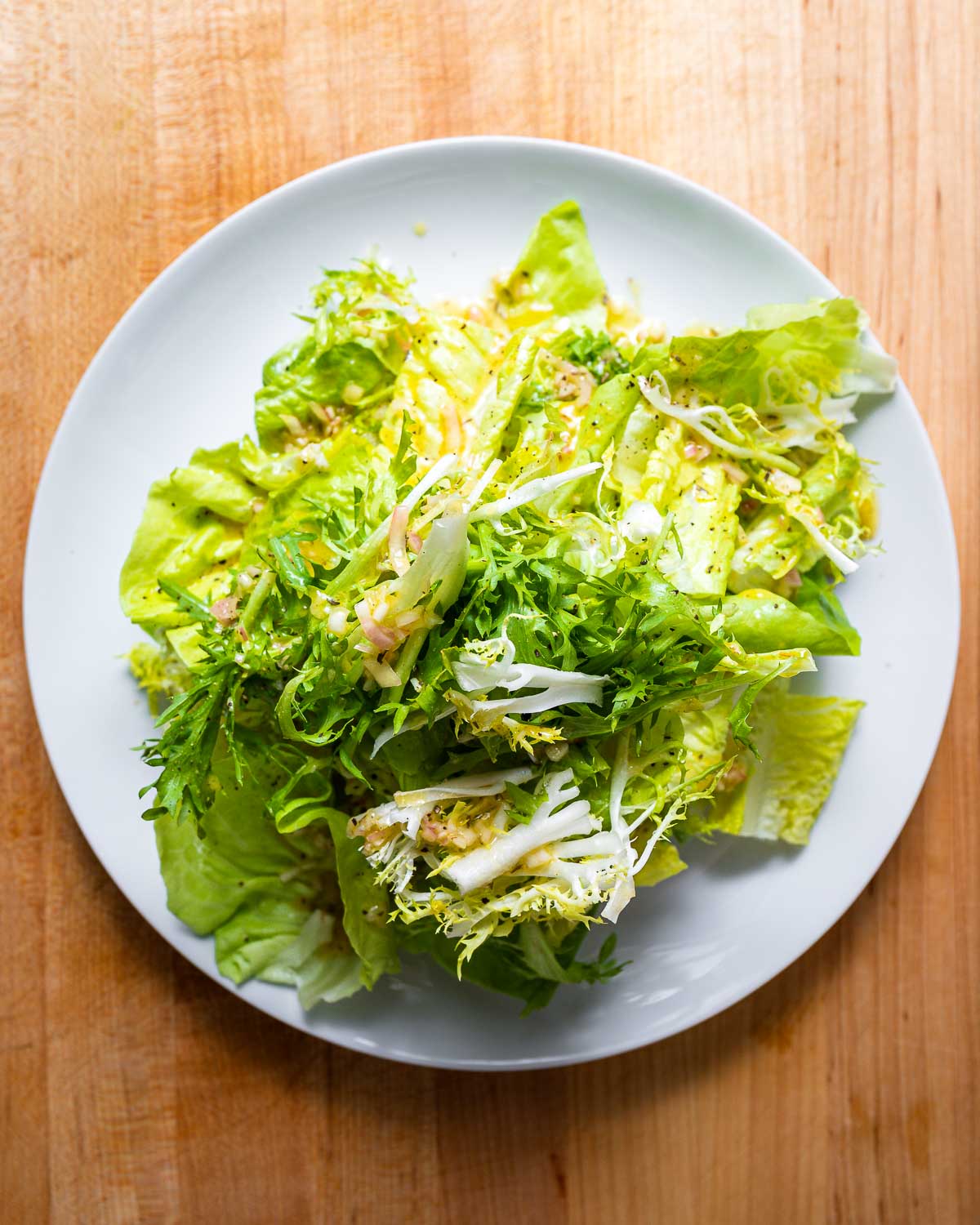 Overhead shot of white plate with 3 types of lettuce.